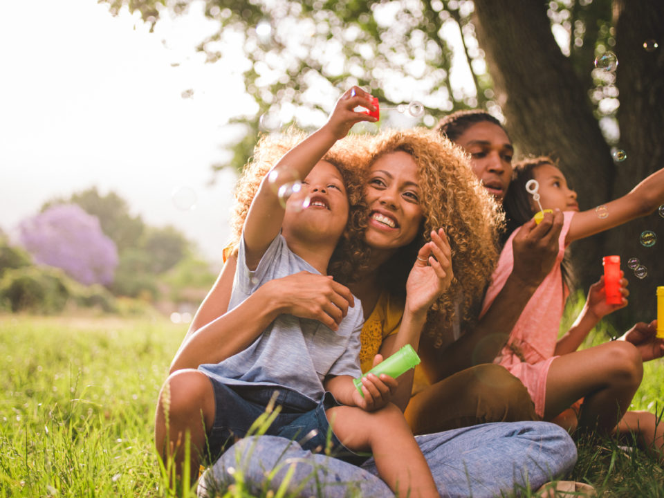 A young family blowing bubbles in the back yard.