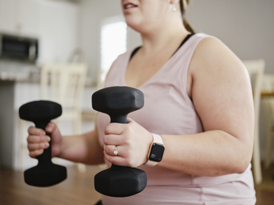 A woman exercising in her home with hand weights.