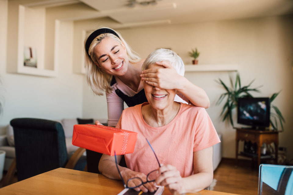 Girl covering mother's eyes and giving her present