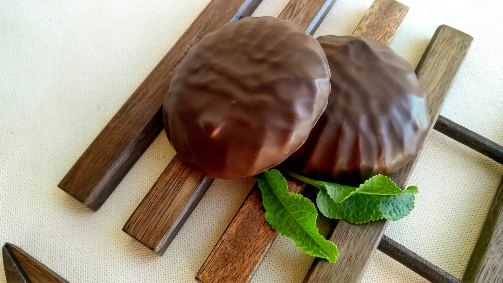 Two chocolate coated peppermint patties with mint leaves