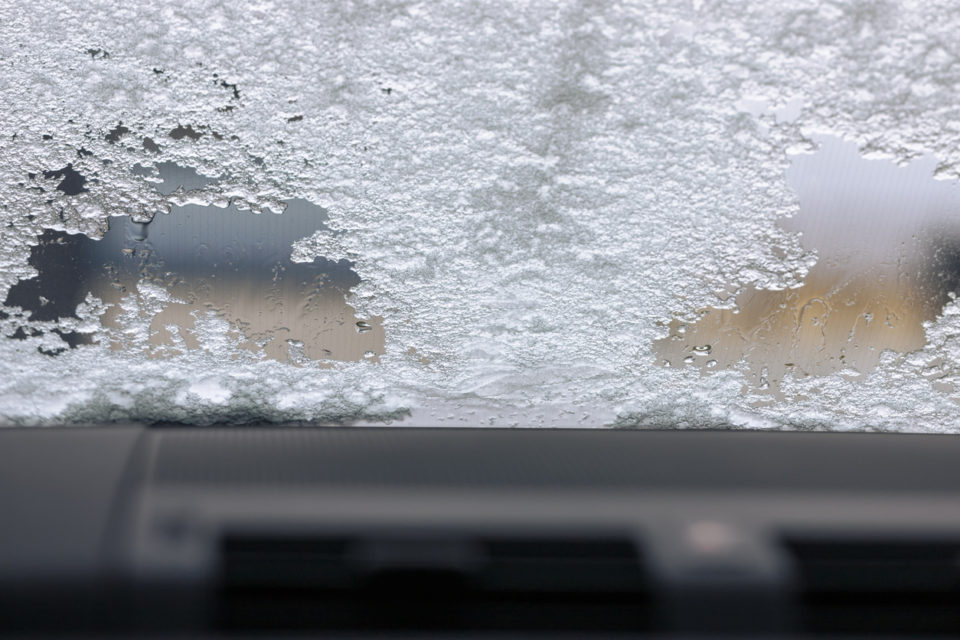 defrosting car windshield with melting ice