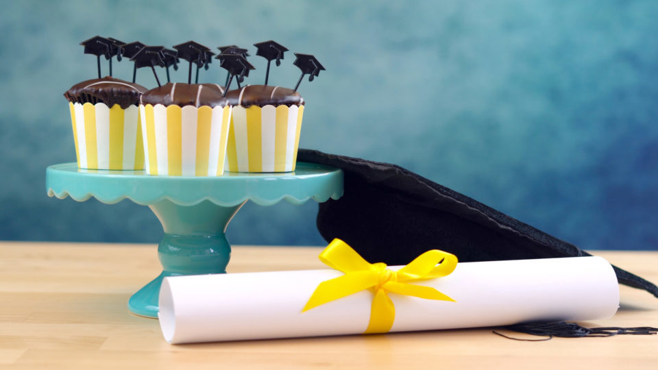 Yellow and blue theme graduation party cupcakes with cap hats toppers and decorations.