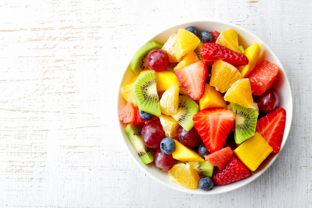 Bowl of fresh fruit salad on wooden background