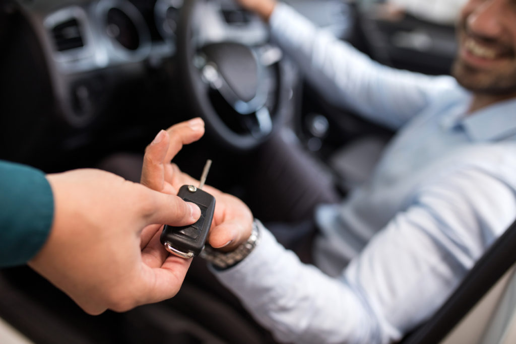 man sitting in a car and receiving car keys